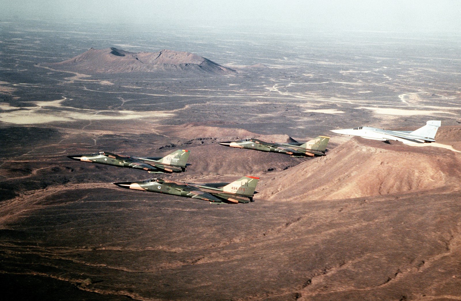 F-111F_aircraft_and_an_EF-111A_Raven_aircraft,_rear,_fly_in_formation_over_the_desert_during_Operation_Desert_Shield._The_aircraft_are_assigned_to_the_48th_Tactical_Fighter_Wing._-_DPLA_-_12aef38d359a02473452f44820076141